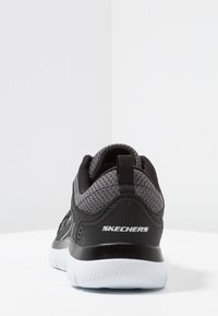 Black athletic shoe with a textured knit upper, a black synthetic heel, and a white rubber outsole. Features a pull tab and Skechers logo.