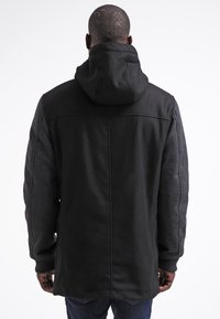 Schwarzer Kapuzenmantel mit einer Mischung aus Stofftexturen, der ein strukturiertes Design, lange Ärmel und einen geraden Schnitt hat, der bis zur Hüfte reicht.