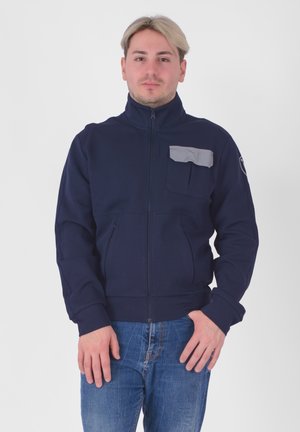 Giacca a zip blu navy con colletto alto, tasca sul petto grigia e polsini abbinati. Presenta un tessuto testurizzato e tasche frontali.