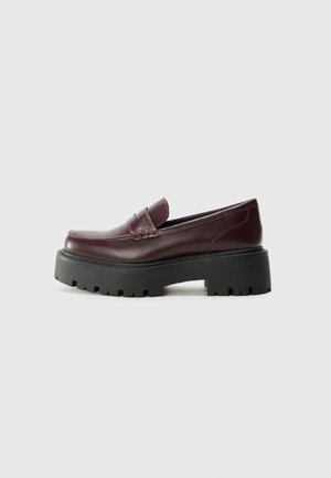 Burgundy leather loafers with a round toe, decorative stitching, and a thick black rubber sole featuring a rugged tread pattern.