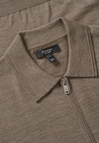 Polo de color marrón con cremallera, hecho de 100% lana merino, con un cuello y una etiqueta que muestra la talla L y la marca Matinique.