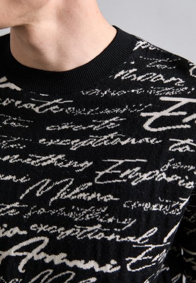 Schwarzer gestrickter Pullover mit einem weißen Schriftmuster, Rundhalsausschnitt und strukturiertem Stoff in einem lässigen Schnitt.