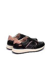 Zapatillas negras y rosas con un upper de cuero brillante, costuras en contraste, un collar acolchado y una suela de goma texturizada. Presenta un detalle de logo.