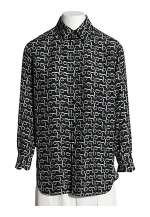 Chemise noire à manches longues boutonnée avec un motif abstrait circulaire et des lignes horizontales blanches sur un torse de mannequin blanc.