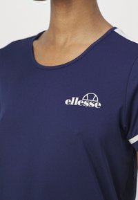 Mörk marinblå t-shirt i mjukt tyg med rund halsringning. Har vita detaljer på ärmarna och en framträdande vit logga på bröstet.