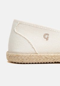 Shoe slip-on bianco in tela con suola in juta intrecciata e un piccolo "G" ricamato sul lato. Tessuto textured con cuciture a vista.