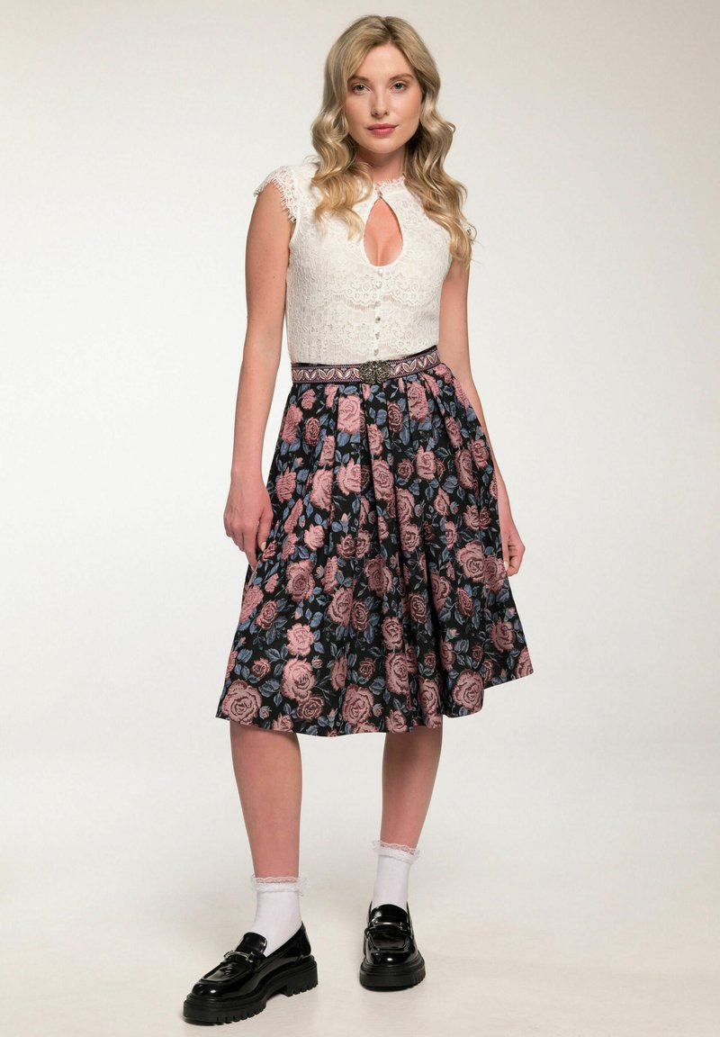 Witte kanten top met een keyhole-halslijn, gecombineerd met een zwart bloemenrok met roze en blauwe rozen. Glanzende zwarte schoenen en witte sokken.
