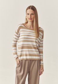 Beige ja valge triibuline kampsun ümmarguse kaeluse ja pikkade varrukatega, valmistatud pehmest kootud materjalist.