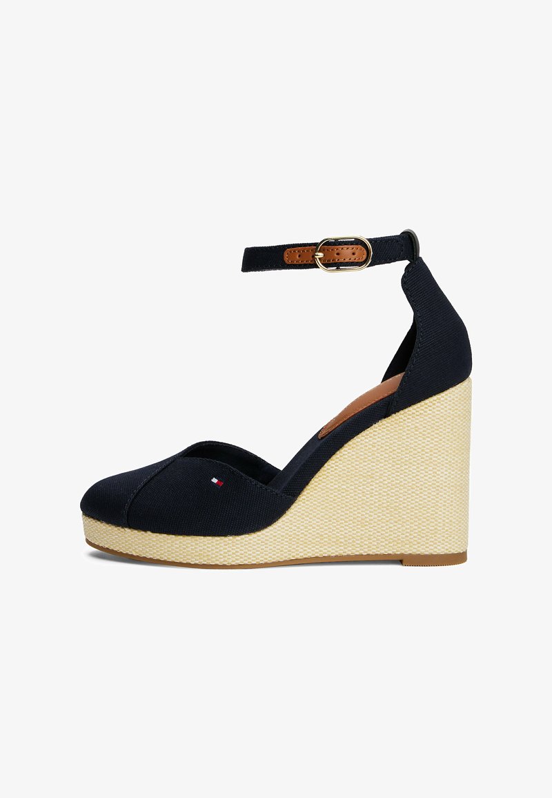 Scarpe wedge in tela blu navy con punta aperta, cinturino alla caviglia e una piattaforma intrecciata beige. Presentano un piccolo logo sulla parte frontale.