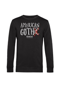 Maglietta nera a maniche lunghe con la scritta "AMERICAN GOTH X WEDNESDAY", caratterizzata da una X rossa sopra la lettera "I" in "GOTHIC".