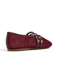 Zapato plano burdeos con punta, lados de malla, dos correas de cuero delgadas con hebillas doradas y una suela marrón.