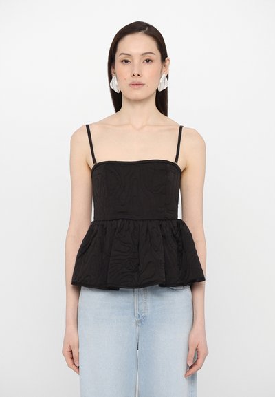 Schwarzes Peplum-Top mit dünnen Spaghetti-Trägern, strukturiertem Stoff und einem formenden Oberteil. Kombiniert mit hellblauen, hoch geschnittenen Jeans.