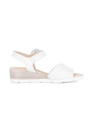 Witte lage sleehak sandaal met open teen, enkelbandje en decoratief gevlochten detail op een effen witte achtergrond.