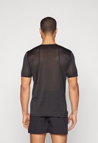 Kortermet svart athletic skjorte med teksturert design, med kontrasterende sømmer, rund halsutringning og avslappet passform.