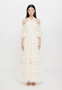 Een lange witte jurk van gerimpeld tulle, met off-shoulder mouwen en een gelaagd ontwerp, met een doorschijnende textuur en een vloeiende silhouet.