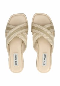 Beige slipper sandalen hebben geweven kruisbanden met een gestreept patroon, een vlakke zool en een reliëf opdruk van het merk op de binnenzool.