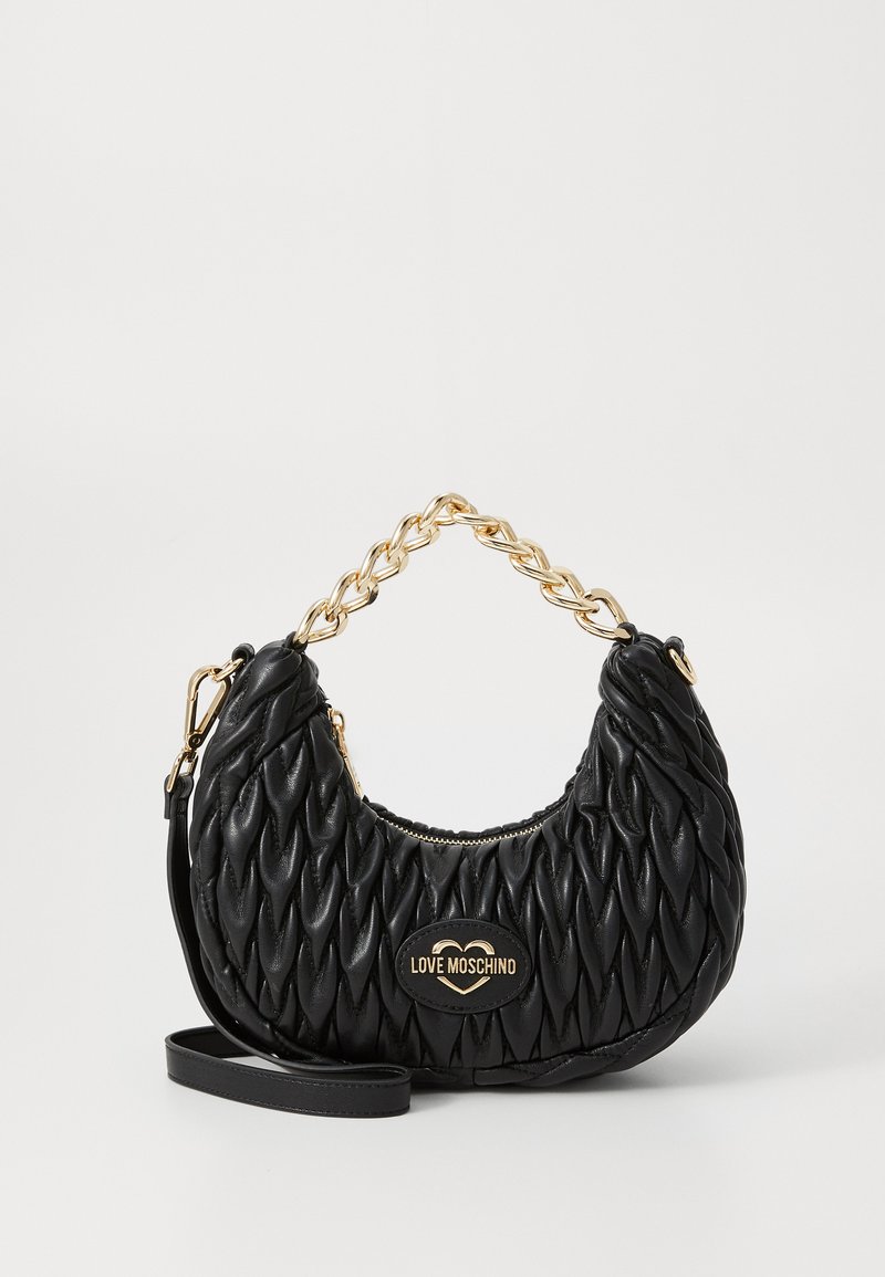 Μαύρη δερμάτινη τσάντα χειρός με καπιτονέ υφή, χρυσό λουρί, και λεπτομέρεια με λογότυπο, διαθέτοντας κλείσιμο με φερμουάρ και ρυθμιζόμενο λουρί.