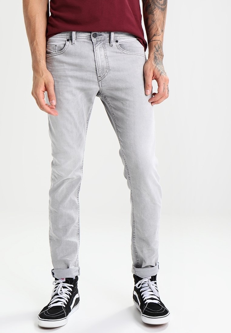 Grå denimjeans med slim fit, som har ljus blekning och strukturerade sömmar, kombinerat med svarta högklackade sneakers och en vinröd skjorta.