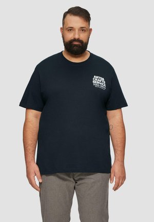 T-shirt en coton bleu marine avec un texte graphique blanc sur la poitrine gauche, col rond et manches courtes. Conception simple et classique.