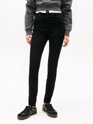 Black high-waisted jeans with a slim fit, made of denim, featuring five pockets, button closure, and stitched detailing. Paired with black sneakers.