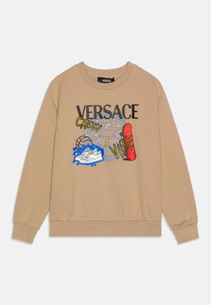 Sudadera beige con texto negro "VERSACE", gráfico de cabeza de Medusa, zapatillas blancas, patineta roja y texto amarillo "CREW" y "VIBE".