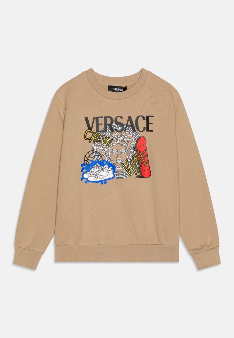 Sweat-shirt beige avec texte noir "VERSACE", graphisme tête de Méduse, baskets blanches, skateboard rouge, et texte jaune "CREW" et "VIBE".