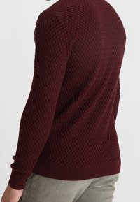 Burgundy stickad tröja med ett strukturerat diamantmönster, ribbade ärmslut och nederkant, slim fit design och långa ärmar.
