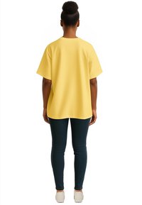 T-shirt giallo over-size con maniche larghe, indossato con jeans scuri e sneakers bianche. Tessuto morbido, vestibilità rilassata e orlo arrotondato.