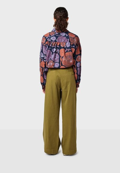 Camicia a maniche lunghe con motivo floreale multicolore, abbinata a pantaloni a gamba larga verde oliva, vista da dietro.
