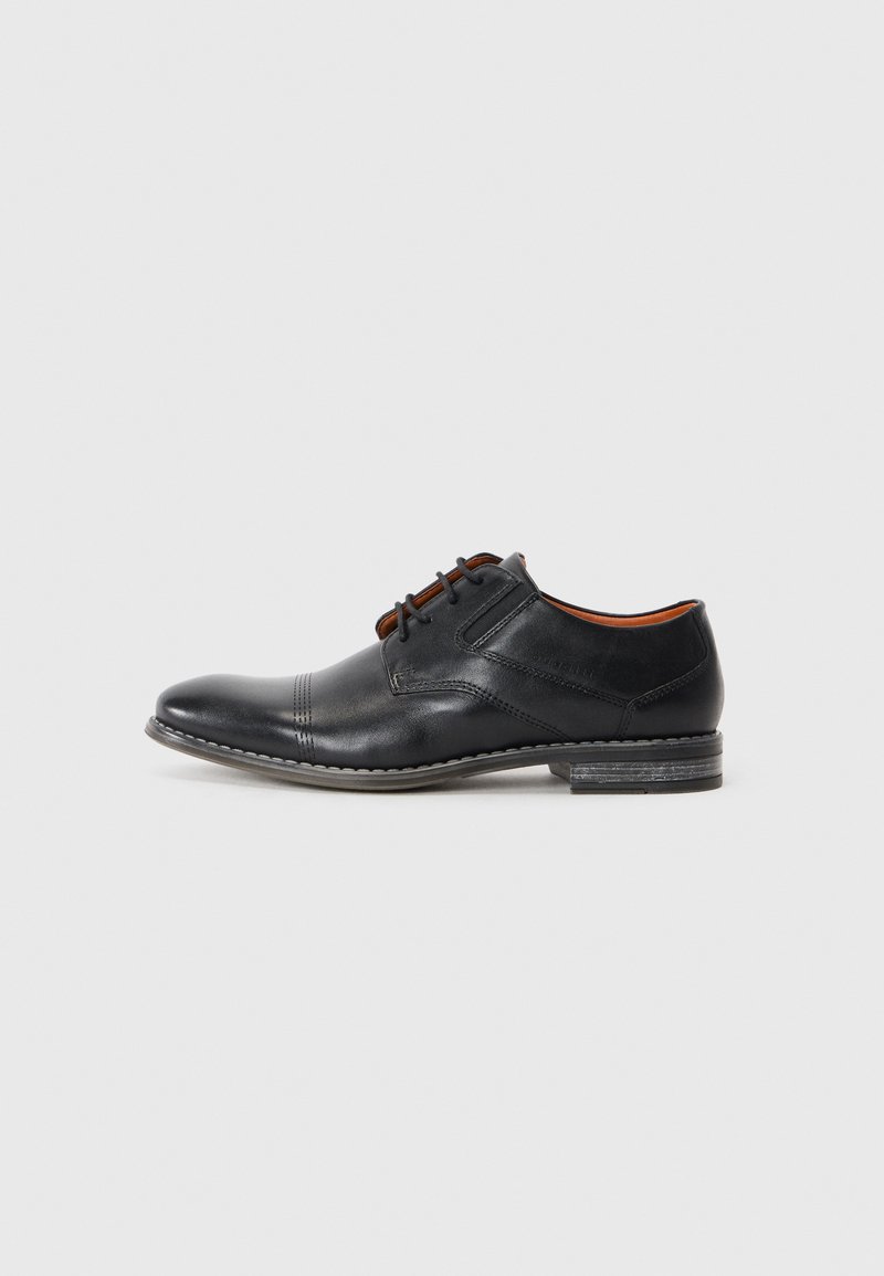 Zapato de vestir de cuero negro con punta redondeada, diseño de cordones y sutiles detalles de costura. Presenta un tacón bajo y una textura suave.