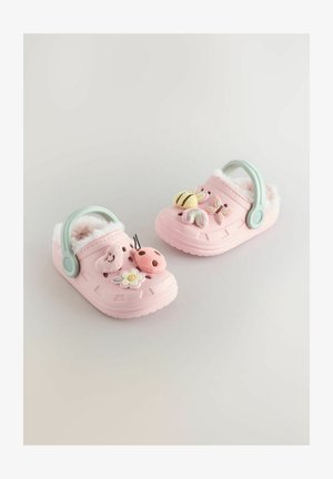 Rosa gummitofflor har en fluffig foder, ett mintgrönt band och dekorativa mjuka utsmyckningar som blommor, insekter och en regnbåge.