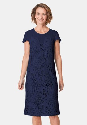 Marineblaue Kleid mit kurzen Ärmeln, das aufwendige Blattschnittmuster und eine taillierte Silhouette aufweist, gefertigt aus strukturiertem Stoff.