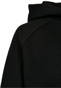 Tissu tricoté noir avec un gros plan sur un col roulé plié et un détail de couture à l'épaule.