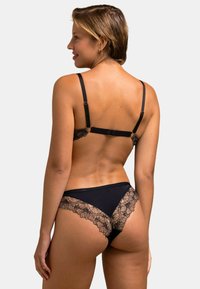 Ensemble de lingerie noir avec des bordures en dentelle, comprenant un bralette avec des bretelles réglables et un string avec des accents en dentelle florale le long des bords.