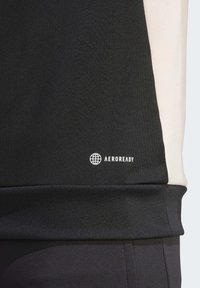 Felpa nera con accenti grigi, dotata di orlo a coste e piccolo logo bianco "AEROREADY". Texture liscia e design atletico.