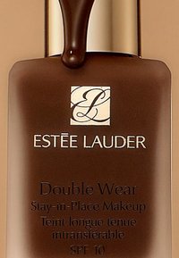 Bouteille en verre brun de maquillage Estée Lauder Double Wear avec un embout pompe. Le texte comprend le nom du produit et un SPF 10. Design épuré et accents brillants.
