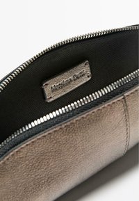 Pochette en cuir marron avec intérieur noir, équipée d'une fermeture éclair argentée et d'une étiquette embossée indiquant "Massimo Dutti." Texture lisse.