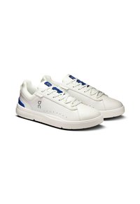 Baskets blanches avec des accents bleus, tige en cuir lisse, lacets plats, détails perforés sur les côtés et semelle en caoutchouc texturé.
