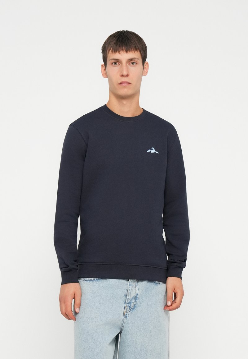 Granatowy sweatshirt z długimi rękawami, okrągłym dekoltem i małym logiem górskim. Wykonany z teksturowanej tkaniny, posiada ściągacze przy mankietach i w pasie.
