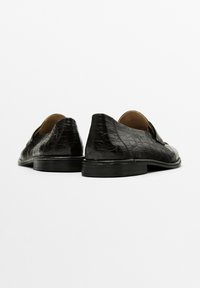Black leather shoes with a textured crocodile pattern, shown from the rear against a white background. Classic style with a rounded heel.