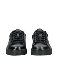 Zwarte leren low-top sneakers met zwarte veters en dikke rubberen zolen, van voren gezien op een witte achtergrond.