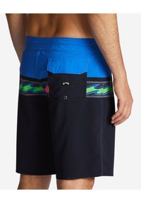 Czarno-niebieskie szorty do pływania mają kolorowy wzór fal i tylną kieszeń z klapką. Wykonane z trwałej, lekkiej tkaniny.
