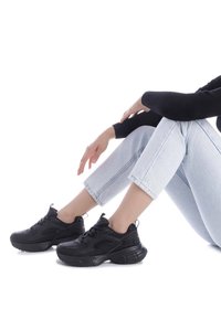 Zapatillas deportivas negras con una suela gruesa, parte superior de textil y sintético, que cuentan con cordones, ventilaciones laterales y una tira en el talón.