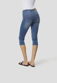 Vidēja ziluma džinsu kapri bikses ar pieguļošu formu un īsu garumu. Kabatām dekoratīvas šuves un viegli nodilis izskats.