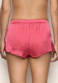Pink satin shorts featuring a comfortable elastic waistband and scalloped hem, with lace accents on the sides for added detail.