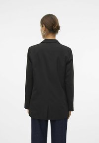Black blazer featuring a notched collar, long sleeves, and a single vent at the back. The fabric appears smooth and structured.