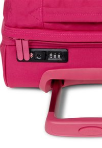 Valigia rosa con esterno in tessuto resistente, doppia cerniera, lucchetto a combinazione e manico retrattile per facilità di trasporto.