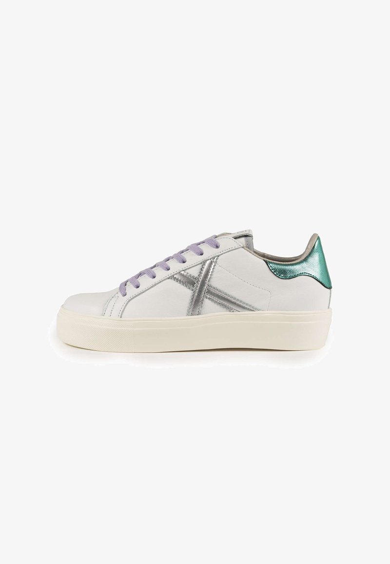 White leather sneaker with silver accents, purple laces, and a teal heel. Features a chunky sole and a sleek design.