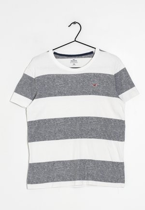 Stripet T-shirt med korte ærmer lavet af bomuld. Vekslende brede navy og hvide striber, rund hals, med et lille broderet logo på brystet.