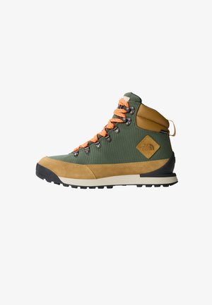 Bota de caminhada com parte superior em lona verde, detalhes em camurça bege, atacadores laranja e sola de borracha para tração. Detalhe de marca presente.